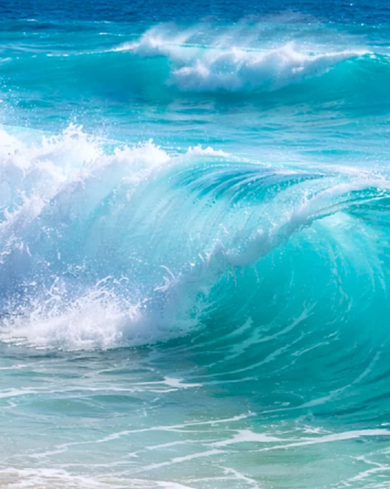 Turquoise ocean wave breaking under a clear sky